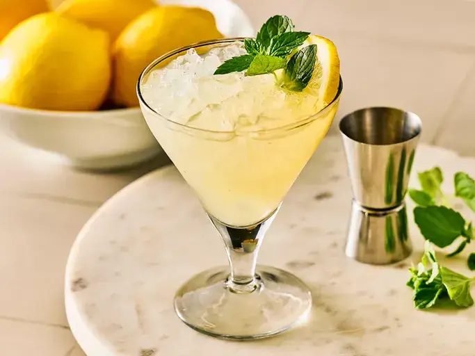 A perfect, professionally made Lemon Drop Martini in a chilled coupe glass with a sugar rim and lemon twist, set on a marble background
