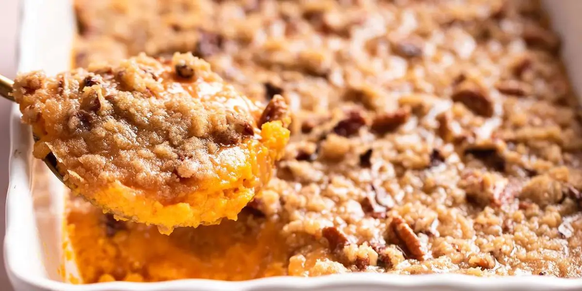 Sweet potato casserole serving on a white plate topped with golden-brown marshmallows, ready to eat.