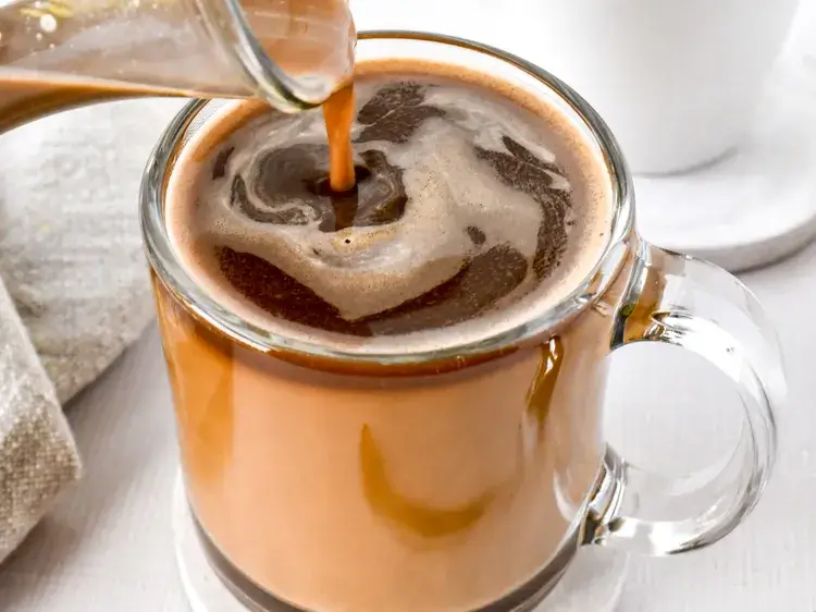 Irish Cream Coffee Creamer being poured into a cup of hot coffee creating cream swirls