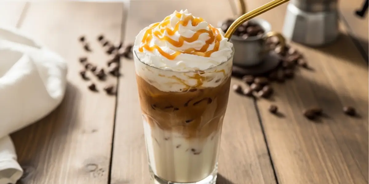 Venti iced white mocha recipe served in a tall clear glass with whipped cream and caramel drizzle on a rustic wooden table
